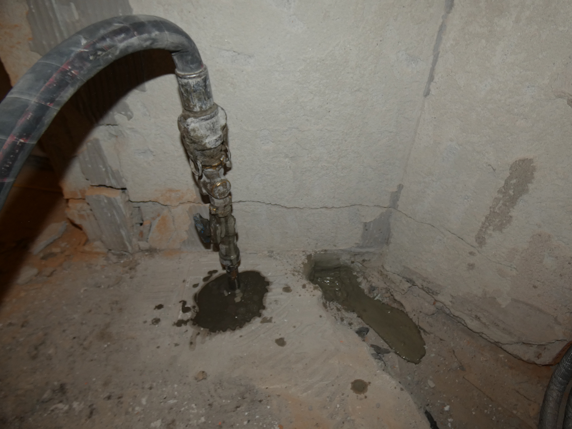 Verstärkung eines Kellers durch Injektion – Bohrlöcher und Materialeinpressung entlang des Fundaments eines alten Gebäudes